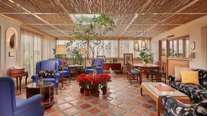 A spacious living area with a high ceiling, large windows, and a central plant arrangement. - The Riviera Hotel (Taipei)