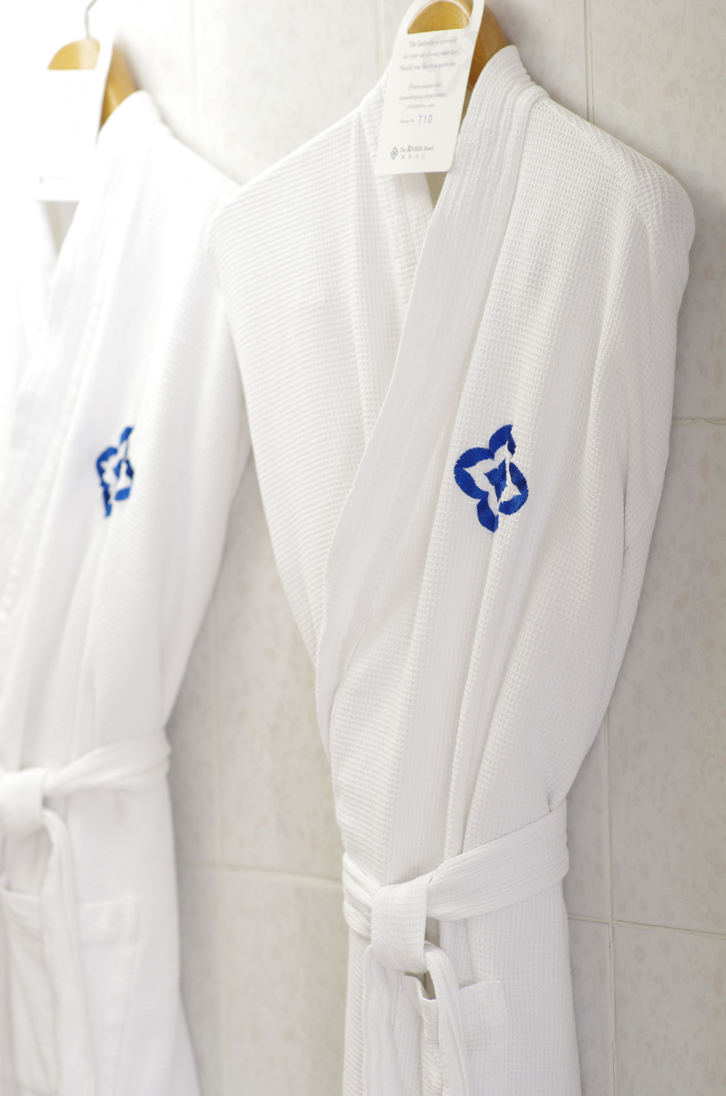 A white robe with a blue logo hanging on a wall.