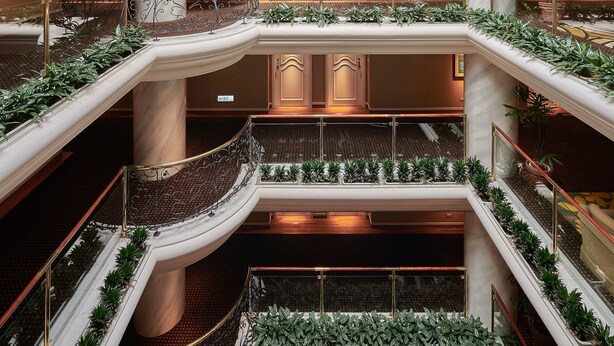 A multi-level atrium with a glass ceiling, multiple balconies, and indoor plants. - The Riviera Hotel (Taipei)