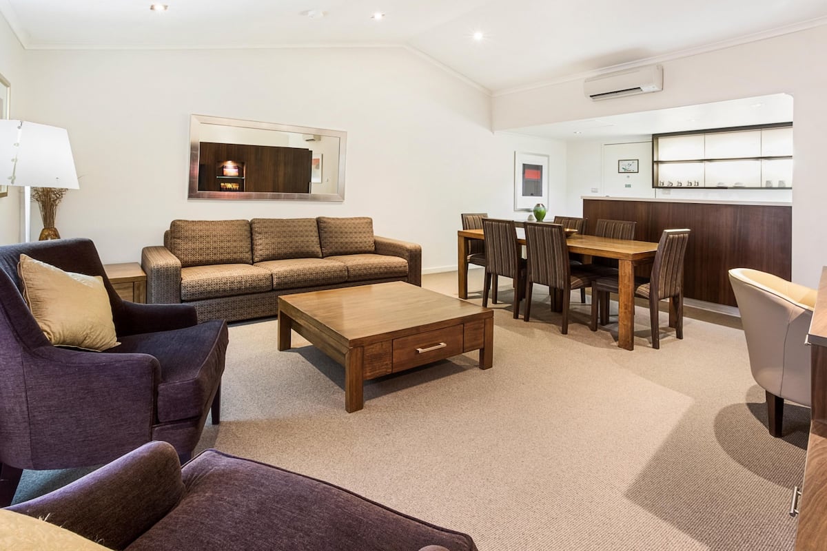 A modern living room with a sofa, coffee table, and dining area.