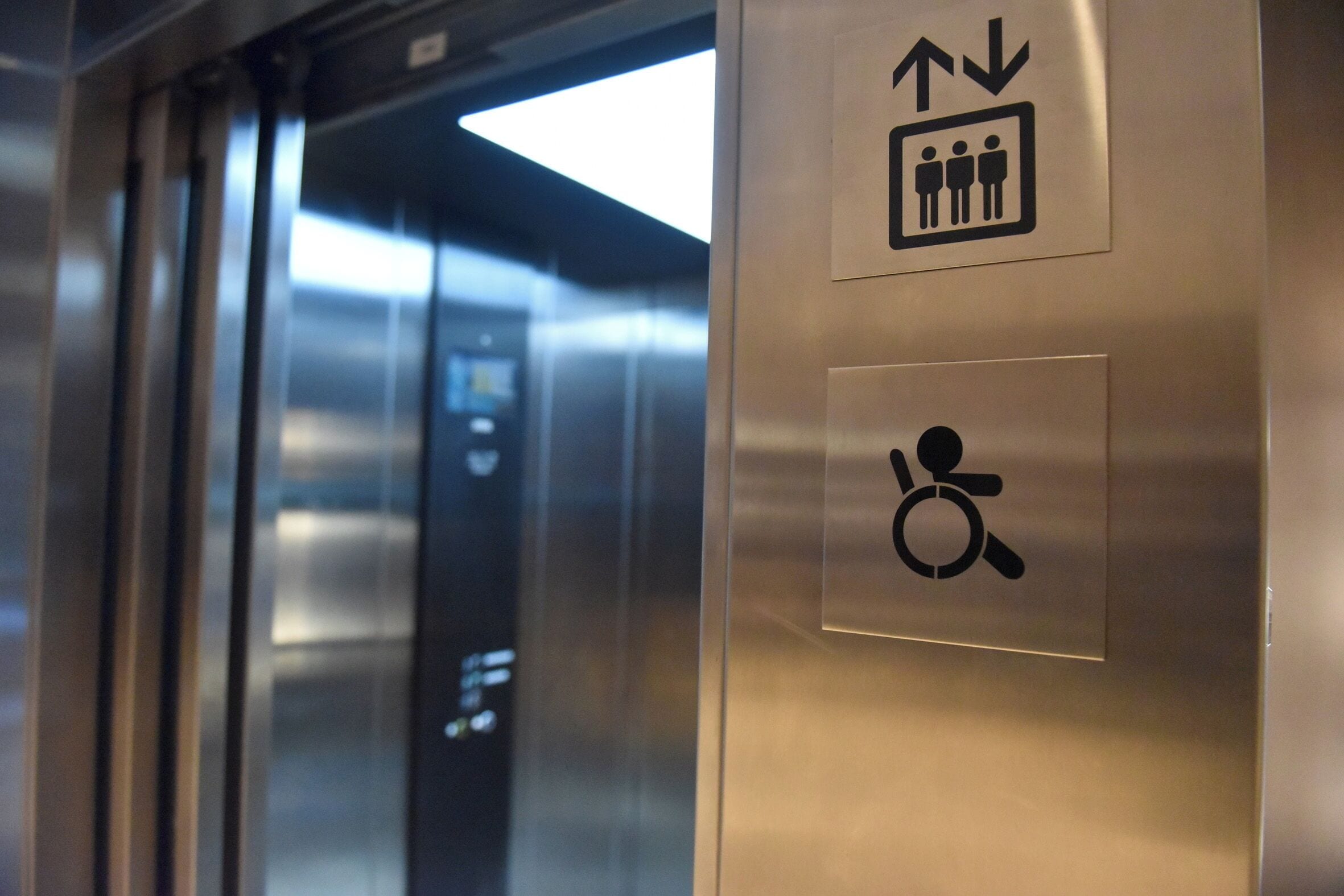 An elevator interior with directional signs and accessibility symbols.