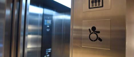 An elevator interior with directional signs and accessibility symbols.