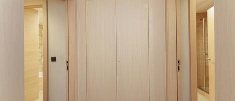 A hallway with a wooden wardrobe, a door with a handle, and a tiled floor.