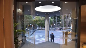 A hotel entrance with glass doors, a modern interior, and a view of the street outside.