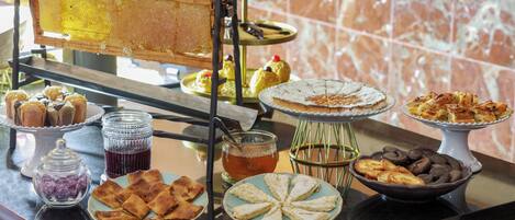 Una mesa de buffet con diversos postres y pasteles, incluyendo panales de miel, tartas y productos cubiertos de chocolate.