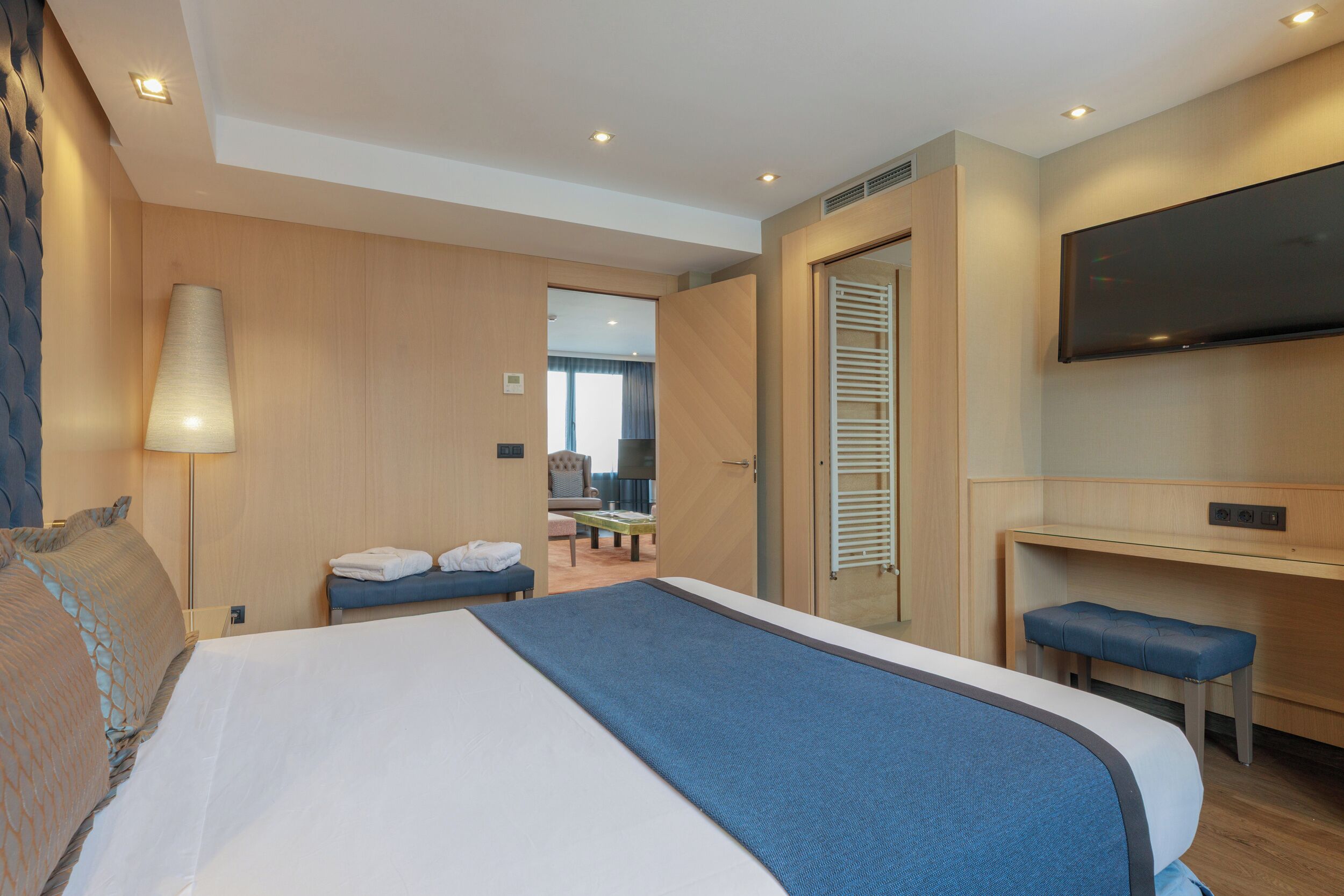 Une chambre d’hôtel avec un grand lit, un bureau avec une chaise, un téléviseur fixé au mur et une fenêtre avec des stores.