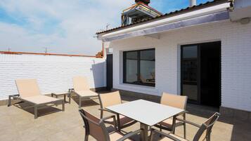 A patio area with outdoor seating and a white brick building.