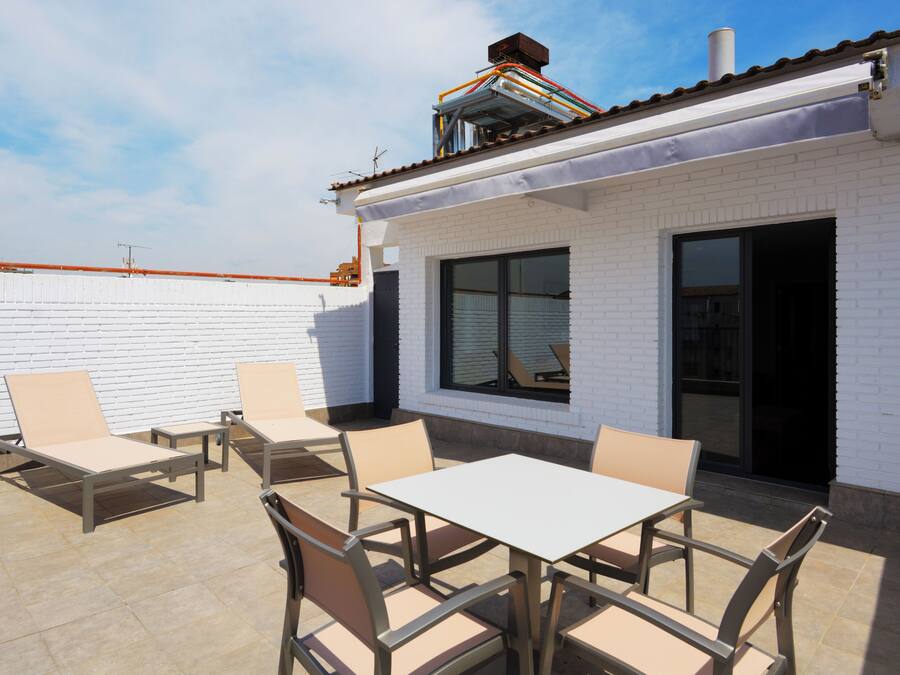 A patio area with outdoor seating and a white brick building.