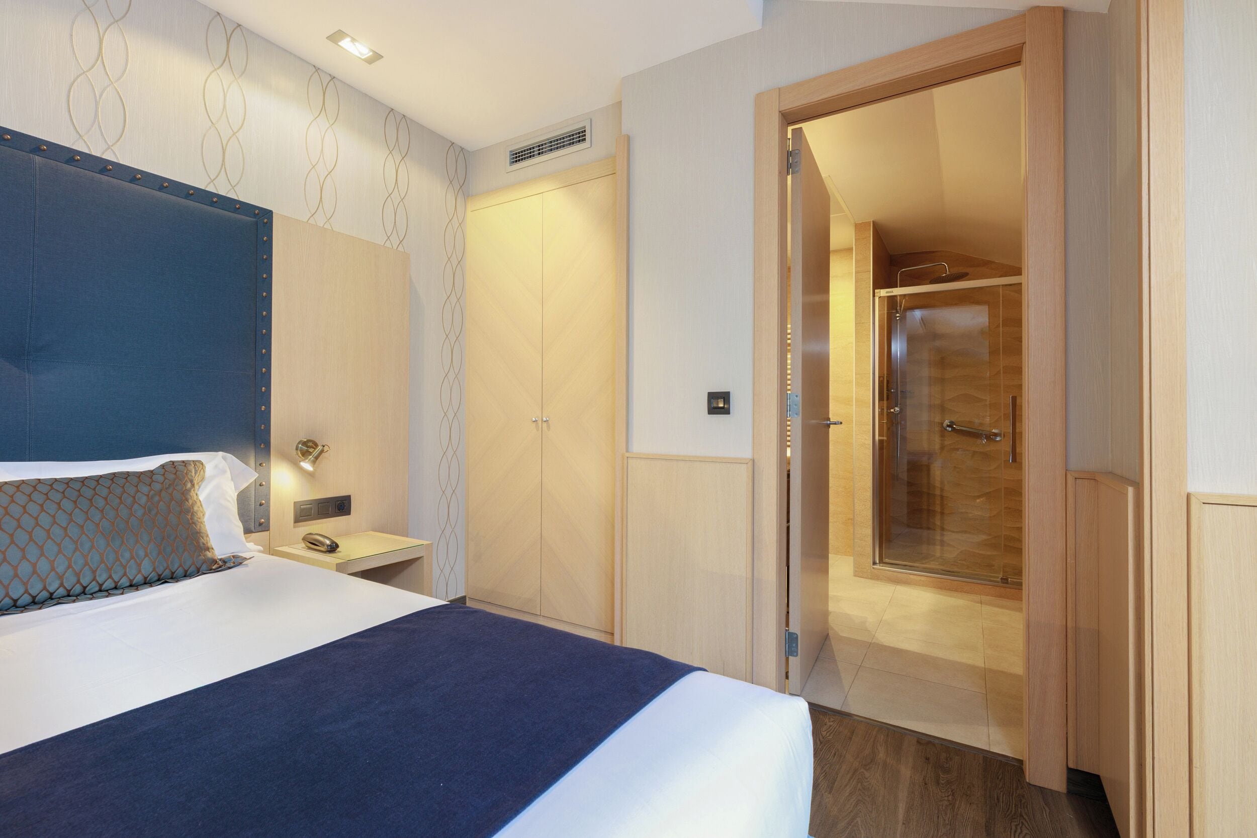 A hotel room with a bed, bedside table, and a walk-in closet.