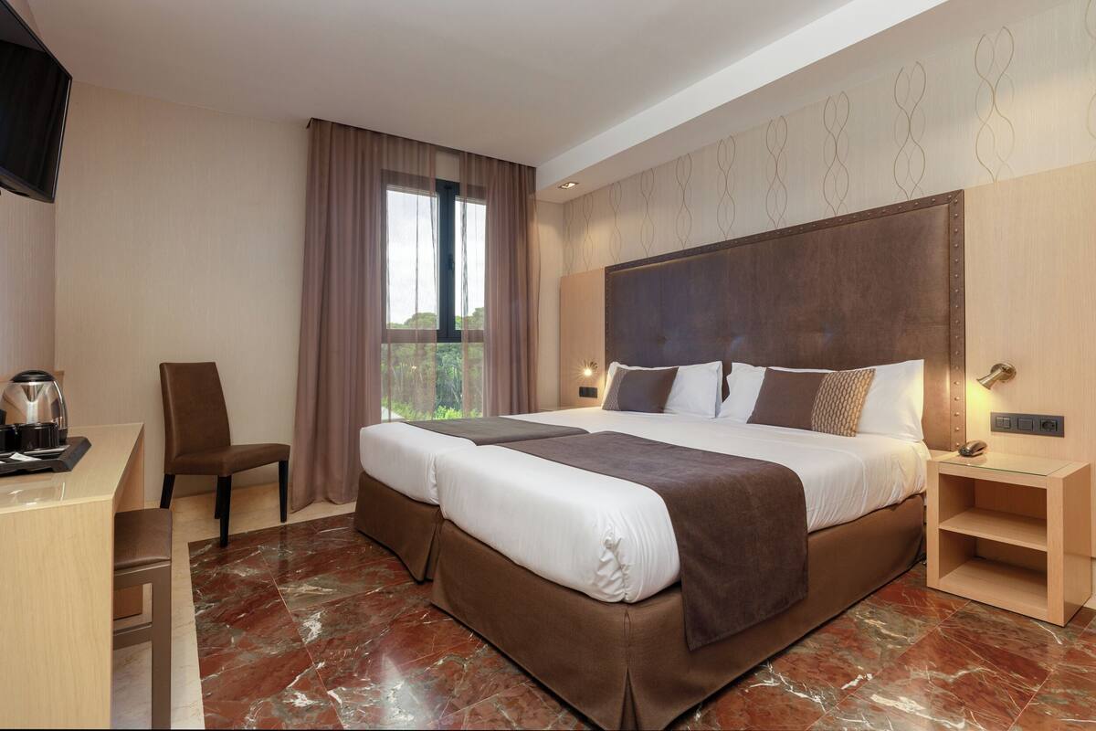 A hotel room with a large bed, a desk, and a chair.