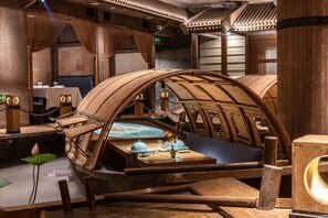 A traditional wooden room with a curved ceiling, a table with a blue tablecloth, and a lotus flower decoration. - Beijing Asia Hotel  (Beijing)