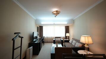 Una habitación de hotel con cama, escritorio, silla, televisor y lámpara.
