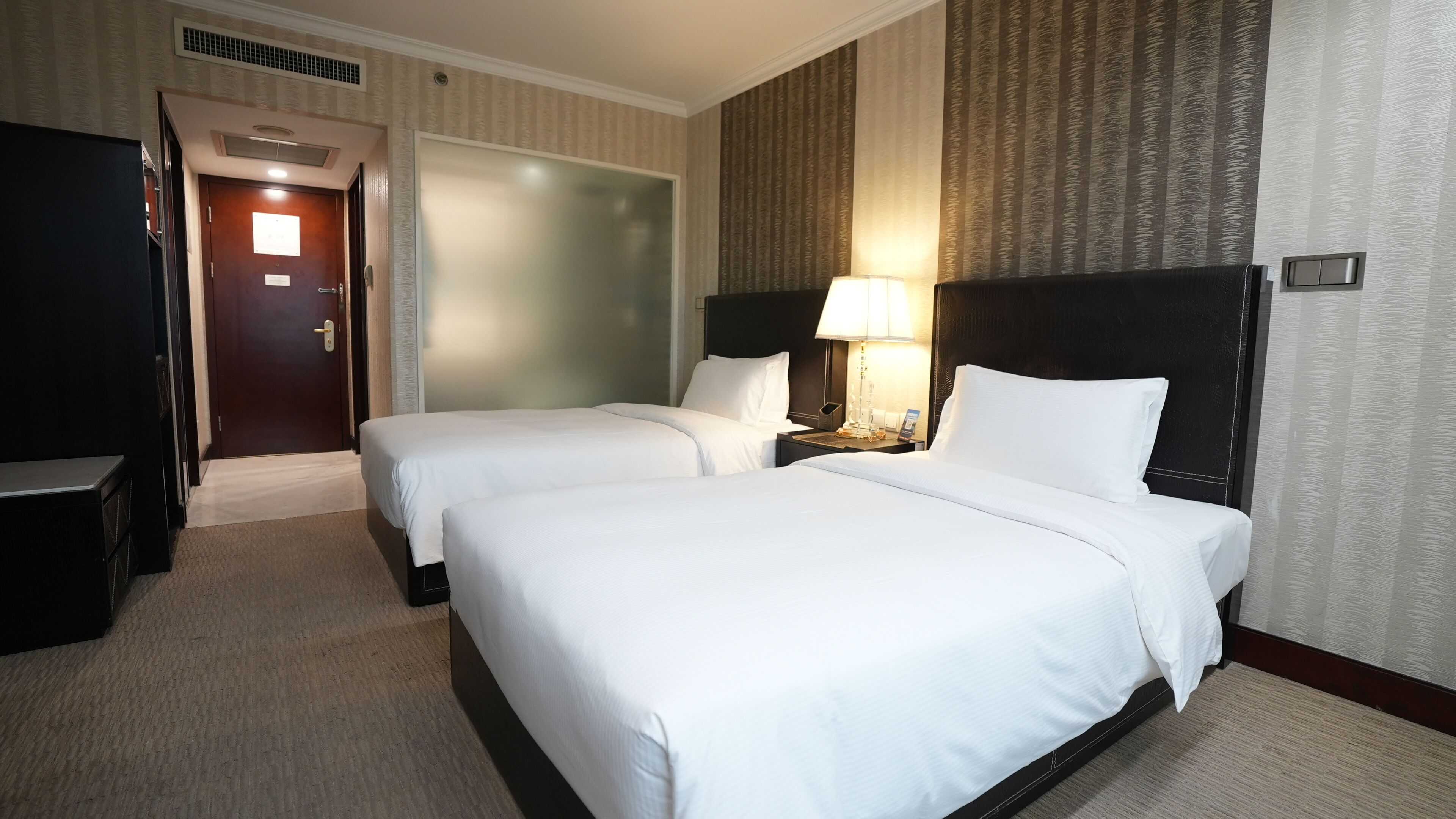 Ett hotellrum med två sängar, ett skrivbord, en garderob och en dörr till badrummet.