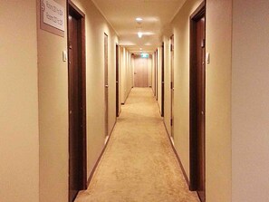 Ein Hotelkorridor mit Türen, die von 21 bis 24 nummeriert sind, einem Teppichboden und einem Schild mit Zimmernummern.