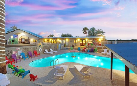 A pool area with lounge chairs and a building with a sign that reads "No Diving Allowed".