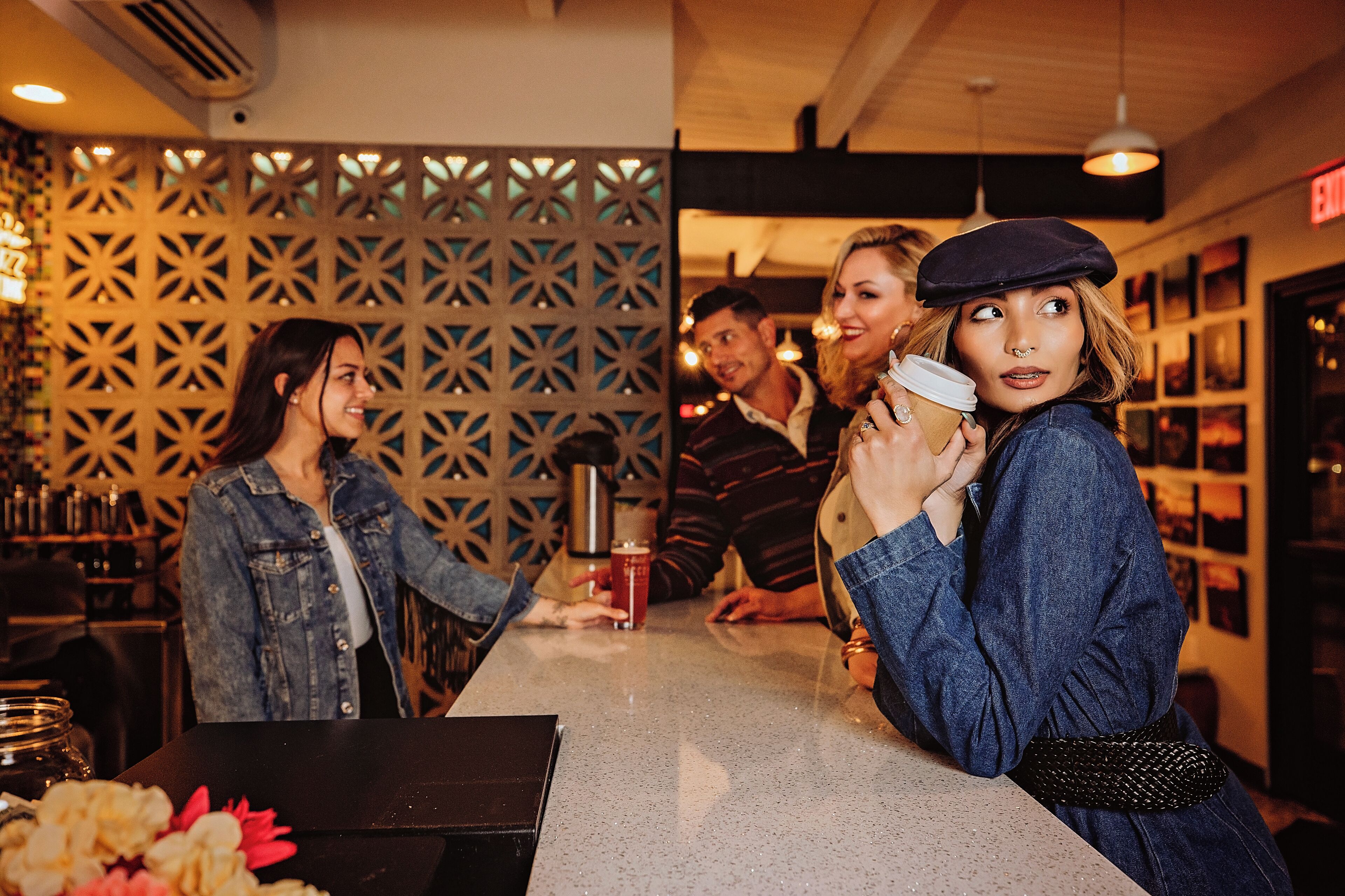 A bar area with a decorative wall, a counter, and a person holding a drink.