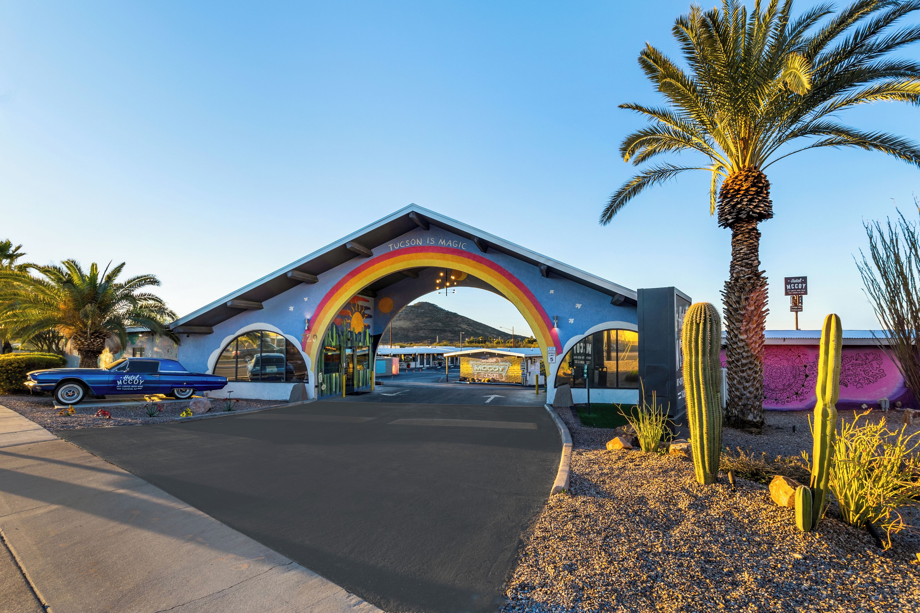 A building with a rainbow archway and a vintage car parked in front.