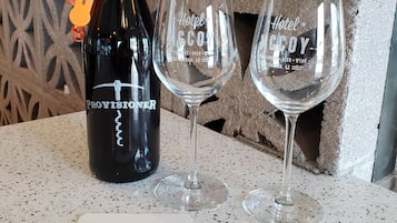 Een fles wijn, twee glaasjes en twee plaatsmatjes met de tekst 'Hotel McCoy' en 'Art, Coffee, Beer, Wine, Tucson, AZ' op een gekleurd aanrecht.
