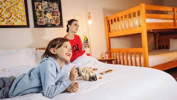 Una habitación con literas, una cama con almohadas, una pared con cuadros enmarcados y una lámpara de pie.