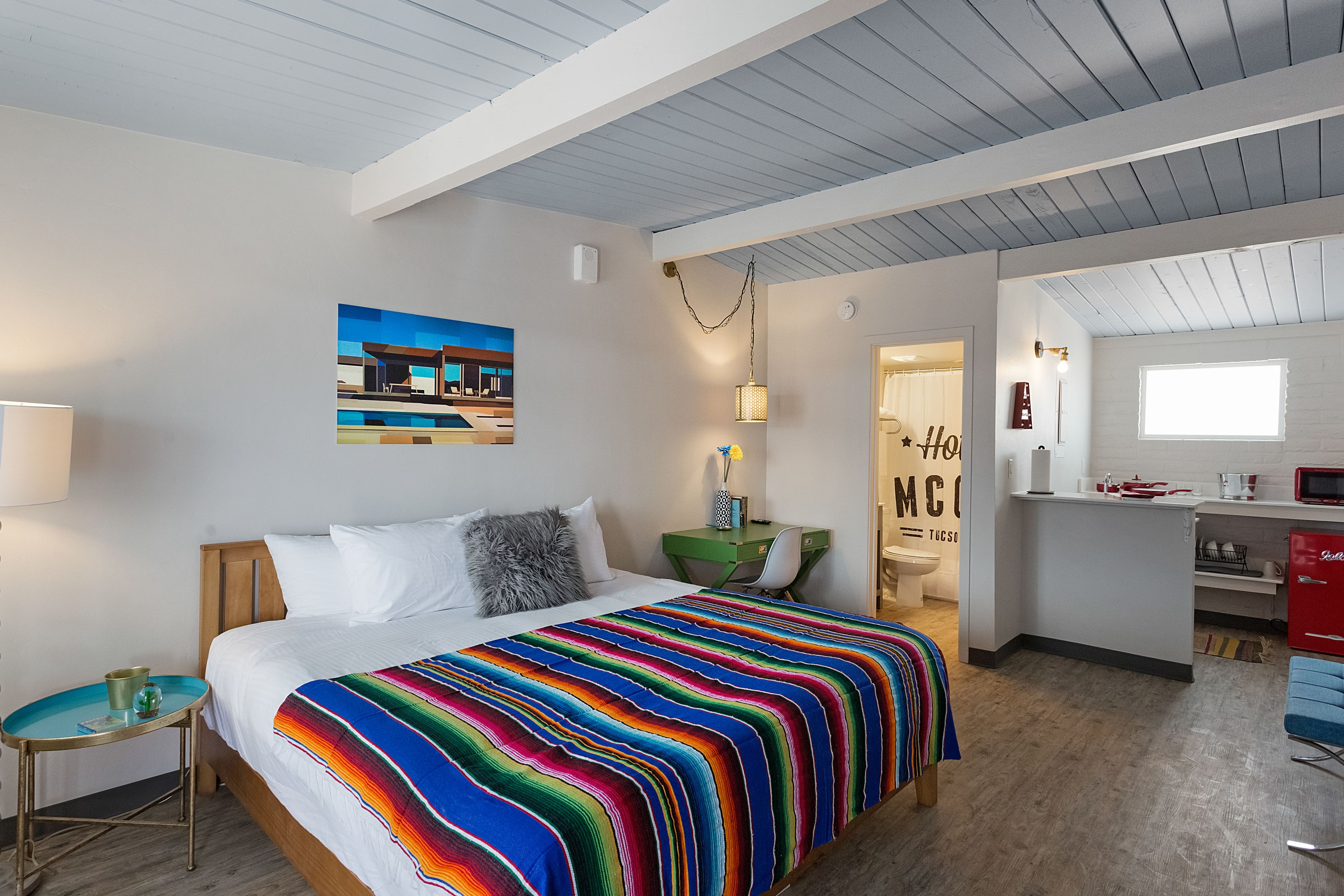 Een moderne hotelkamer met een groot bed, een bureau en een kitchenette.