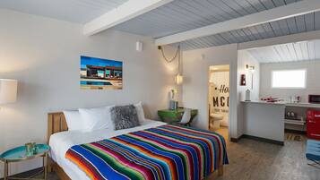 Een moderne hotelkamer met een groot bed, een bureau en een kitchenette.