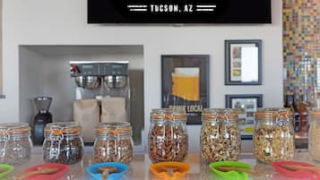 Un comptoir où sont exposés divers pots contenant des noix et des graines, une machine à café et une affiche faisant la publicité d’œuvres d’art, de café, de bière et de vin à Tucson, en Arizona.