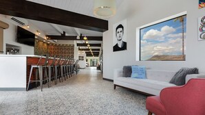 A modern interior with a white sofa, red chair, and patterned floor tiles. - Hotel McCoy Tucson - Art, Coffee, Beer, Wine (Tucson)