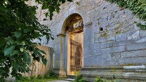 A stone pathway leading to an arched doorway with a metal gate, surrounded by greenery. - Hotell St Clemens (Visby)