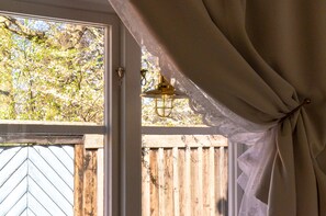 A window with a view of a wooden fence and a tree. - Hotell St Clemens (Visby)
