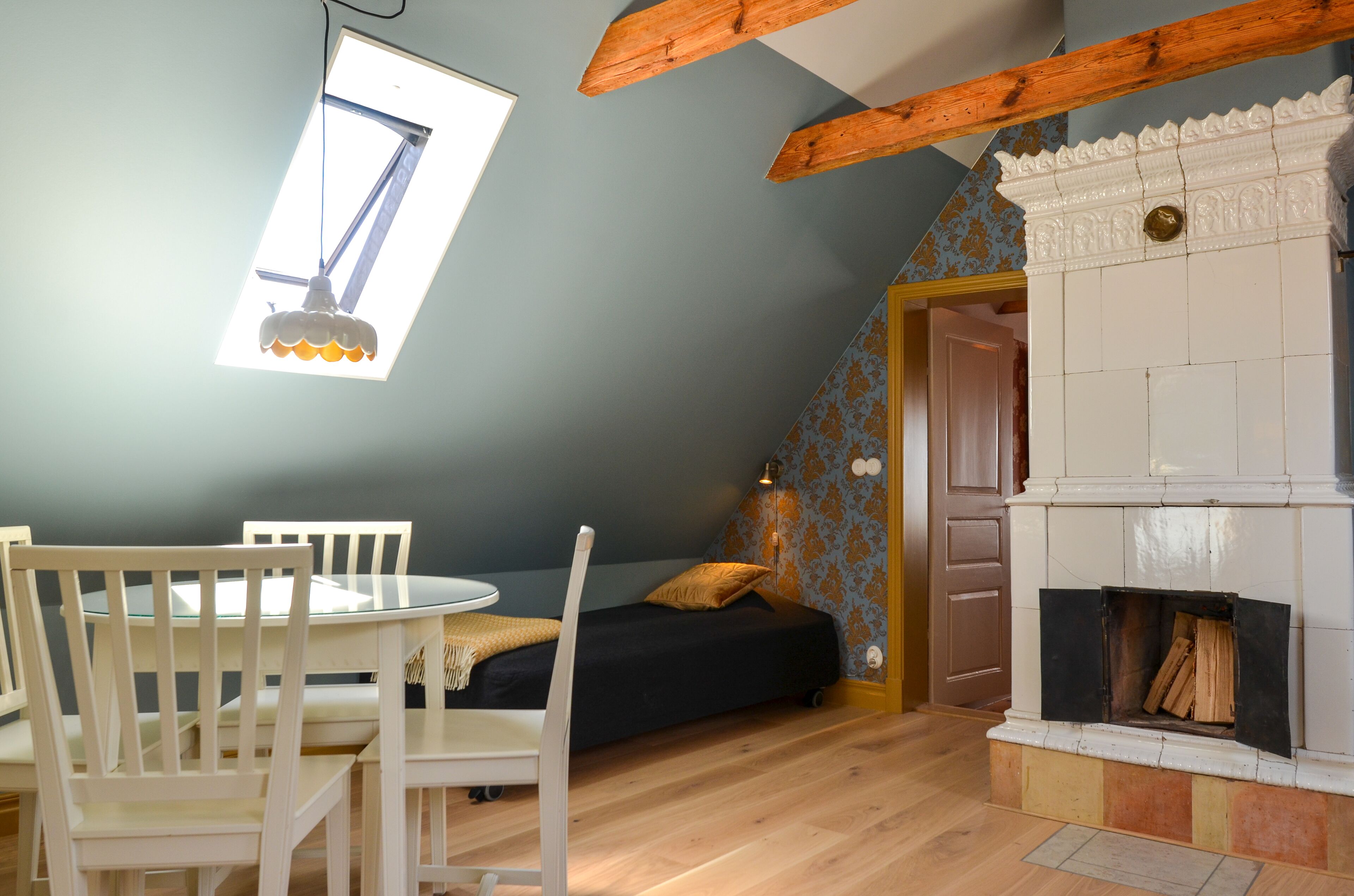 A room with a skylight, a fireplace, a bed, and a dining area with chairs and a table.