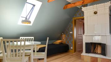 A room with a skylight, a fireplace, a bed, and a dining area with chairs and a table.