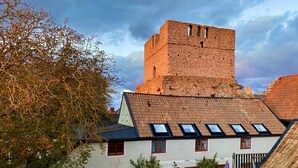 A traditional building with a tower, a courtyard with a table and chairs, and a staircase. - Hotell St Clemens (Visby)