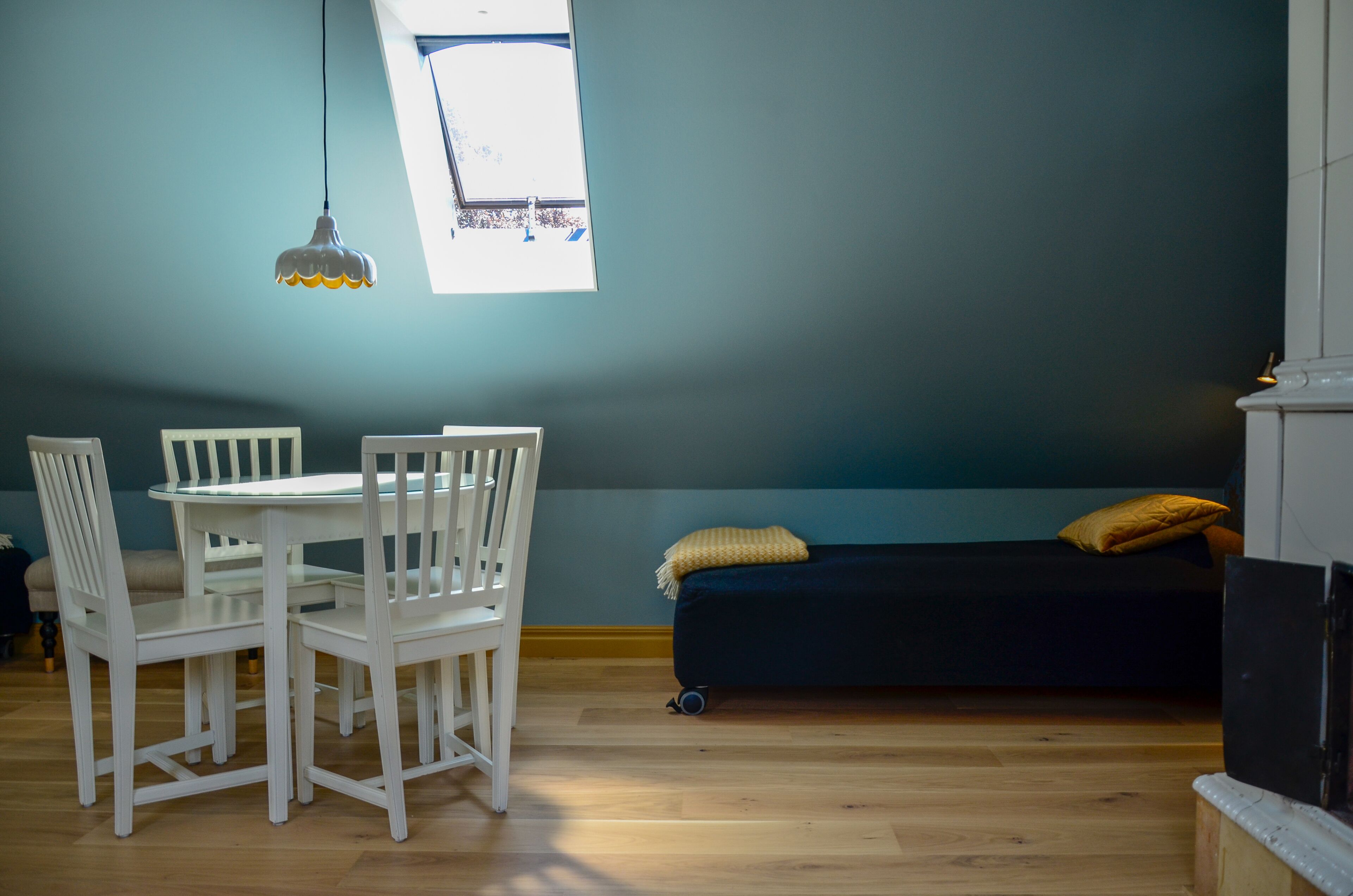 A room with a dining table and chairs, a dark sofa with cushions, and a window with a view.