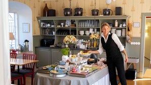 A dining area with a buffet setup, including a variety of food items and a person serving. - Hotell St Clemens (Visby)