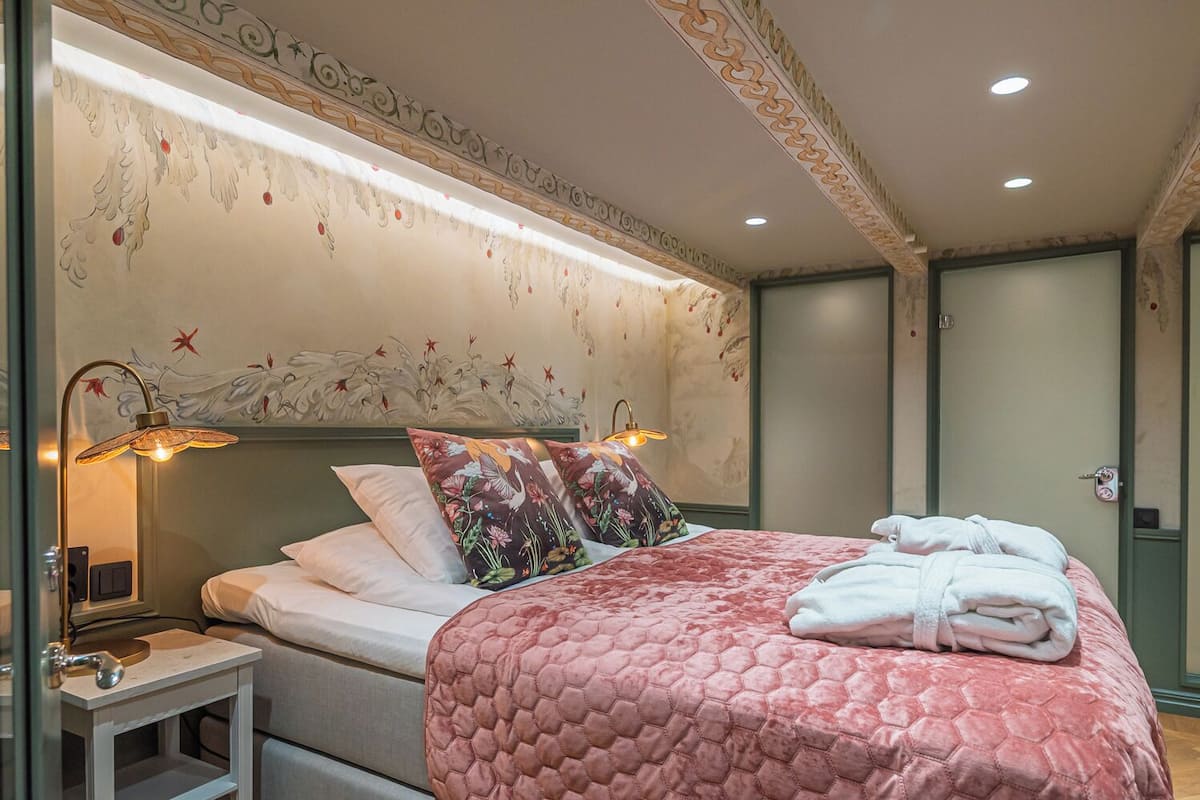 A hotel room with a large bed, floral wall decor, and two bedside lamps.