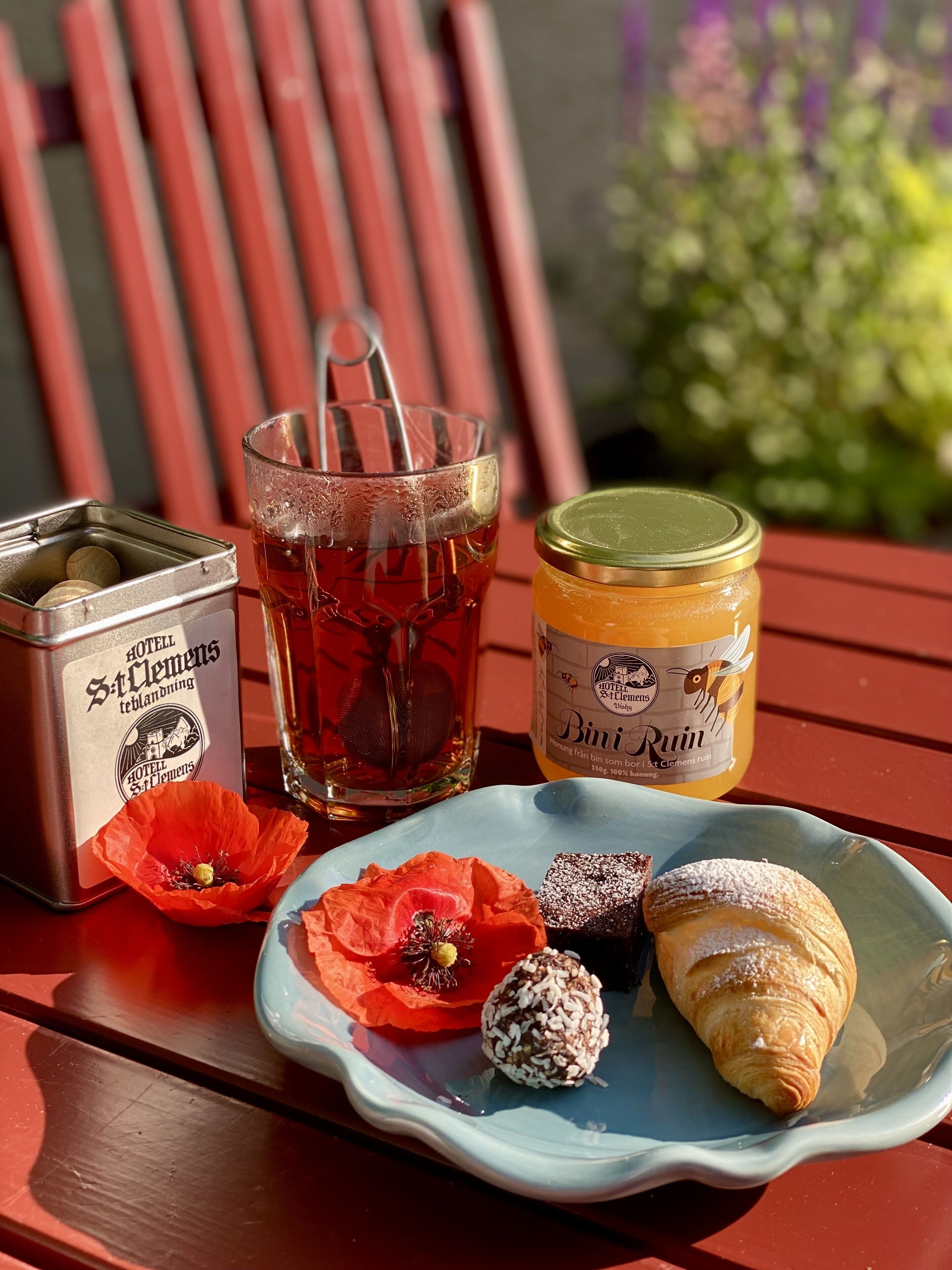 A table with a tea set, a jar of honey, a plate with pastries, and a box of tea bags.