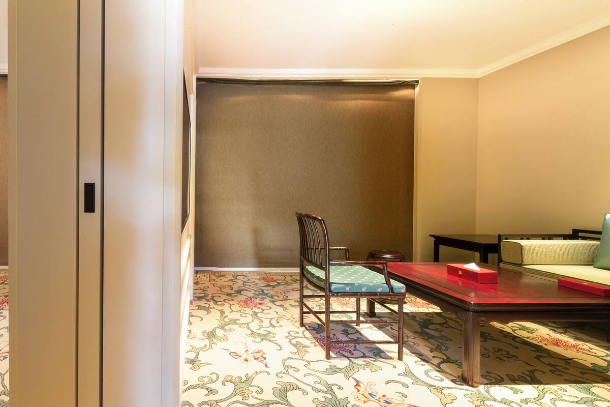 A hotel room with a bed, a dining table, a sofa, and a chair.