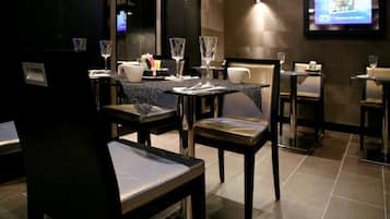 Ein Restaurant mit gedeckten Tischen, Stühlen und einem Fernseher im Hintergrund.