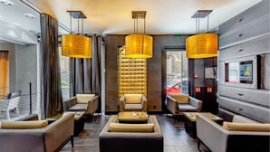 A modern interior with leather sofas, a central tufted chair, and pendant lighting. - L'adresse (Paris)
