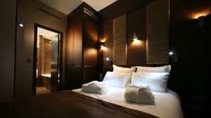 A hotel room with a large bed, two wall-mounted lights, and a door leading to a bathroom. - L'adresse (Paris)