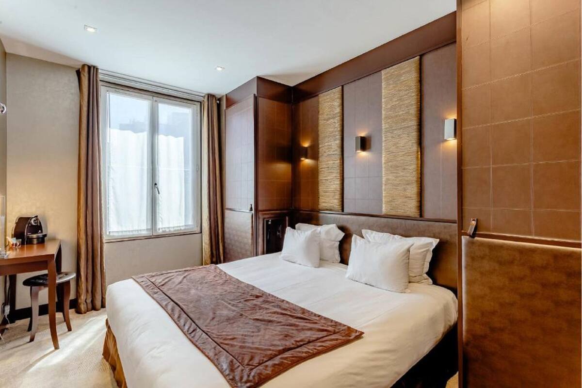 Une chambre d’hôtel avec un grand lit, un bureau et une fenêtre avec des rideaux.