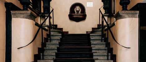 A grand staircase with ornate railings and a decorative lion head at the top.