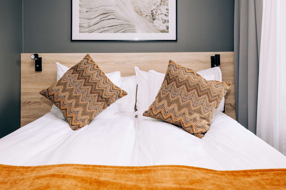 A neatly made bed with patterned pillows and a framed artwork above it.
