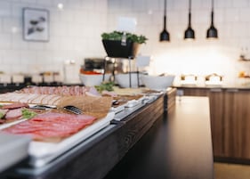 A buffet with various meats and a potted plant in the background.
