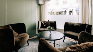Et værelse med to sofaer, et rundt bord med en vase og et vindue med gardiner.