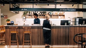 Et barområde med reception, barstole samt diverse flasker og glas på hylder.