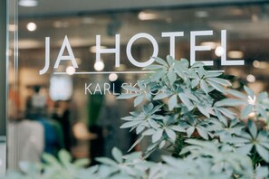 Señal de hotel con el nombre "JA HOTEL" y "KARLSKI" visible a través de una ventana.