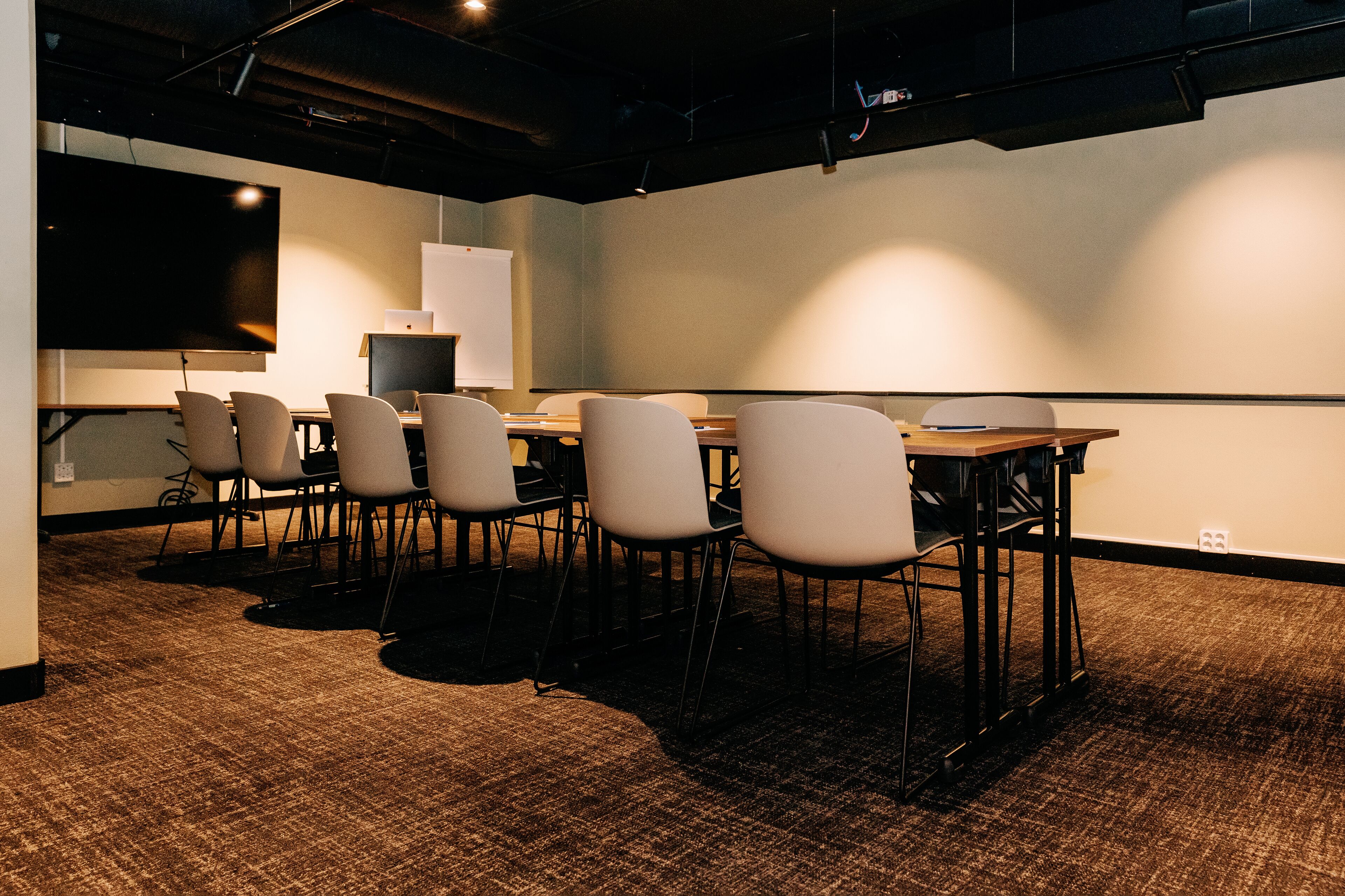 A conference room with a large table, six chairs, a projector screen, and a whiteboard.