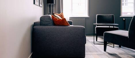 Una sala de estar moderna con un sofá gris, una mesita redonda y una silla.