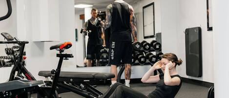 Un gimnasio con equipo de ejercicio, un espejo y una persona haciendo abdominales.